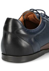 Granatowe skórzane buty z brązowymi akcentami, z perforowanym wzorem i gładką fakturą. Niski profil gumowej podeszwy i widoczne zapięcie na sznurowadła.