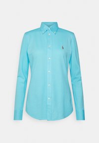 Camisa de manga larga azul claro con cuello abotonado, que presenta un pequeño logo de polo bordado en el pecho y cierre de botones en la parte delantera.