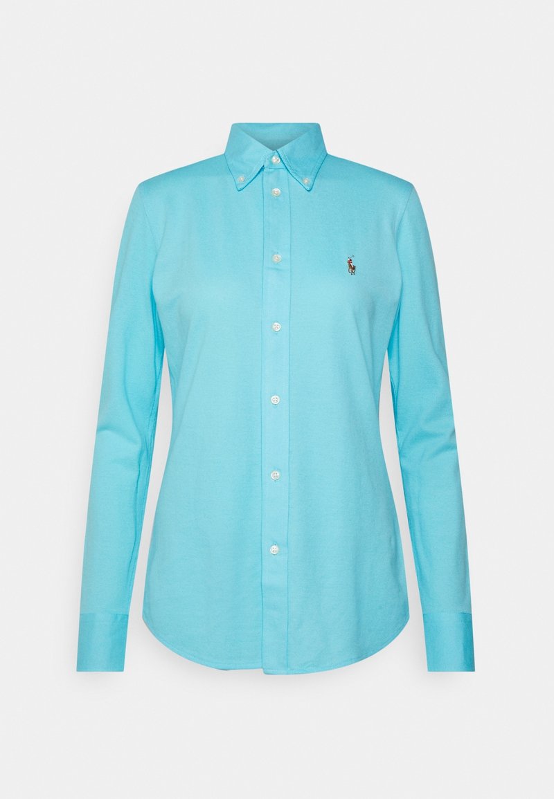 Camisa de manga larga azul claro con cuello abotonado, que presenta un pequeño logo de polo bordado en el pecho y cierre de botones en la parte delantera.