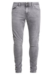Jeans de denim gris con un ajuste slim, diseño de cinco bolsillos y una sutil textura desgastada. Incluye un cierre de botón y trabillas para el cinturón.