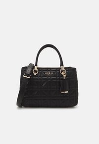 Černá prošívaná kabelka s dvojitými uchy, odnímatelným ramenním popruhem, zlatým kováním a logem "GUESS EST 1981" na přední straně.