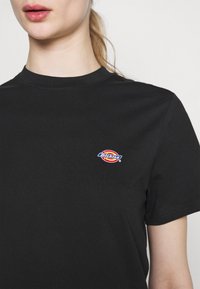 Černé bavlněné tričko s kulatým výstřihem. Na levé části hrudníku má vícebarevné vyšívané logo "Dickies".