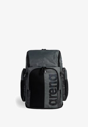 Szary plecak z czarnymi akcentami, wyposażony w dużą przednią kieszeń, siatkowe detale oraz wiele zamykanych na zamek kieszeni do przechowywania.