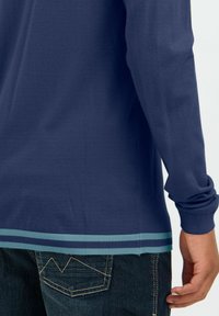 Garais piedurkņu tumši zilais krekls ar ribotiem aprocēm un strīpota apakšmala gaiši zilā un tumši zilā krāsā. Audums izskatās mīksts un ar gludu tekstūru.