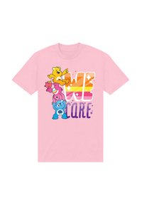 Ljusrosa t-shirt i bomull med färgglada tecknade björnar staplade ovanför texten "VI BRYR OSS" i fet stil med gradientbokstäver och gnistrande effekter.