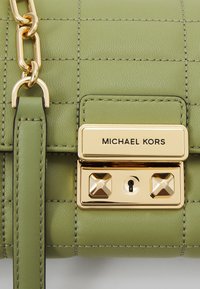 Borsa a tracolla in pelle verde con superficie trapuntata, hardware dorato con borchie e chiusura a lucchetto. Include una tracolla in pelle rimovibile.