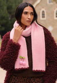 Ružová rebrovaná šatka s vlnitými okrajmi, zdobená dekoratívnou čerešňou, skombinovaná s textúrovaným vínovým kabátom.