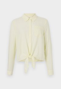 Chemise jaune pâle à manches longues avec col et boutons sur le devant. Elle présente un ourlet noué et une petite poche poitrine en tissu texturé.