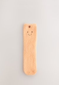 Pehme sünteetilisest materjalist pastelselt virsikuvärvi pliiatsikotike, millel on naeratava näo kujundus, ümar top ja pehme tekstuur.