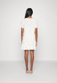 Vestido com padrão floral, base branca, mangas curtas e saia em camadas. Tecido macio, corte descontraído e leve babado na bainha.