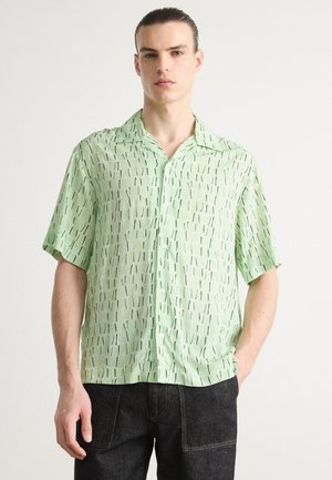 Chemise à manches courtes en tissu vert clair avec un motif de lignes noires verticales, boutonnière à l'avant et un col classique.