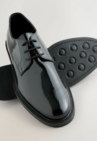 Czarne lakierowane buty na sznurówki o gładkim wykończeniu, zaokrąglonym nosie, płaskiej podeszwie z okrągłymi wzorami antypoślizgowymi oraz wyjmowaną wkładką.
