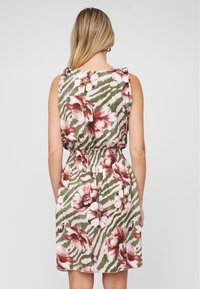 Robe florale avec un motif vert, rose et blanc. Présente une taille smockée et des volants aux épaules, fabriquée en tissu doux et léger.