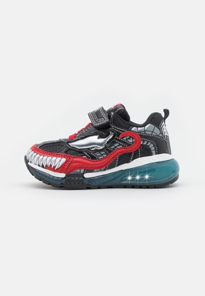 Sort og rød børnesneaker med hvidt tændesign på tåen, sølv dinosaur detalje, velcrorem og gennemsigtig blå polstret sål.
