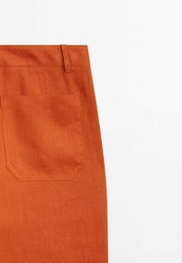 Rustoranje stoffen broek met een textuurafwerking, voorzien van een achthoekige achterzak en ceintuurlussen.