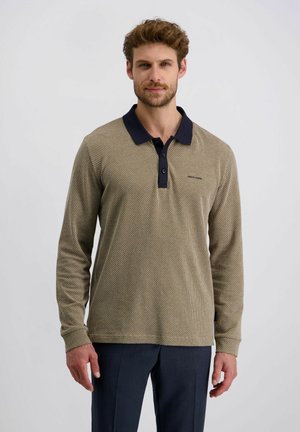 Beige langlopende poloshirt met een gestructureerd patroon, marineblauwe kraag, drieknopensluiting en een gebrandmerkte afwerking op de linkerbust; gecombineerd met donkere broeken.