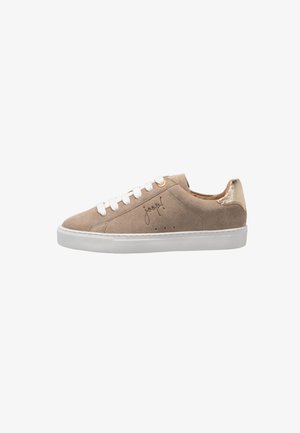 Beige suede low-top sneaker with white laces, white sole, gold heel tab, and a signature detail on the side.