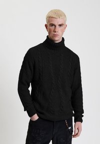 Zwarte kabelgebreide coltrui met geribde manchetten en zoom. Heeft een gestructureerd patroon en is gemaakt van een dikke, warme stof.