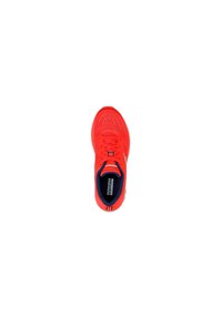 Zapatilla deportiva roja con parte superior de malla transpirable, puntera redondeada y suela texturizada. El interior presenta un forro azul oscuro y una etiqueta de la marca.