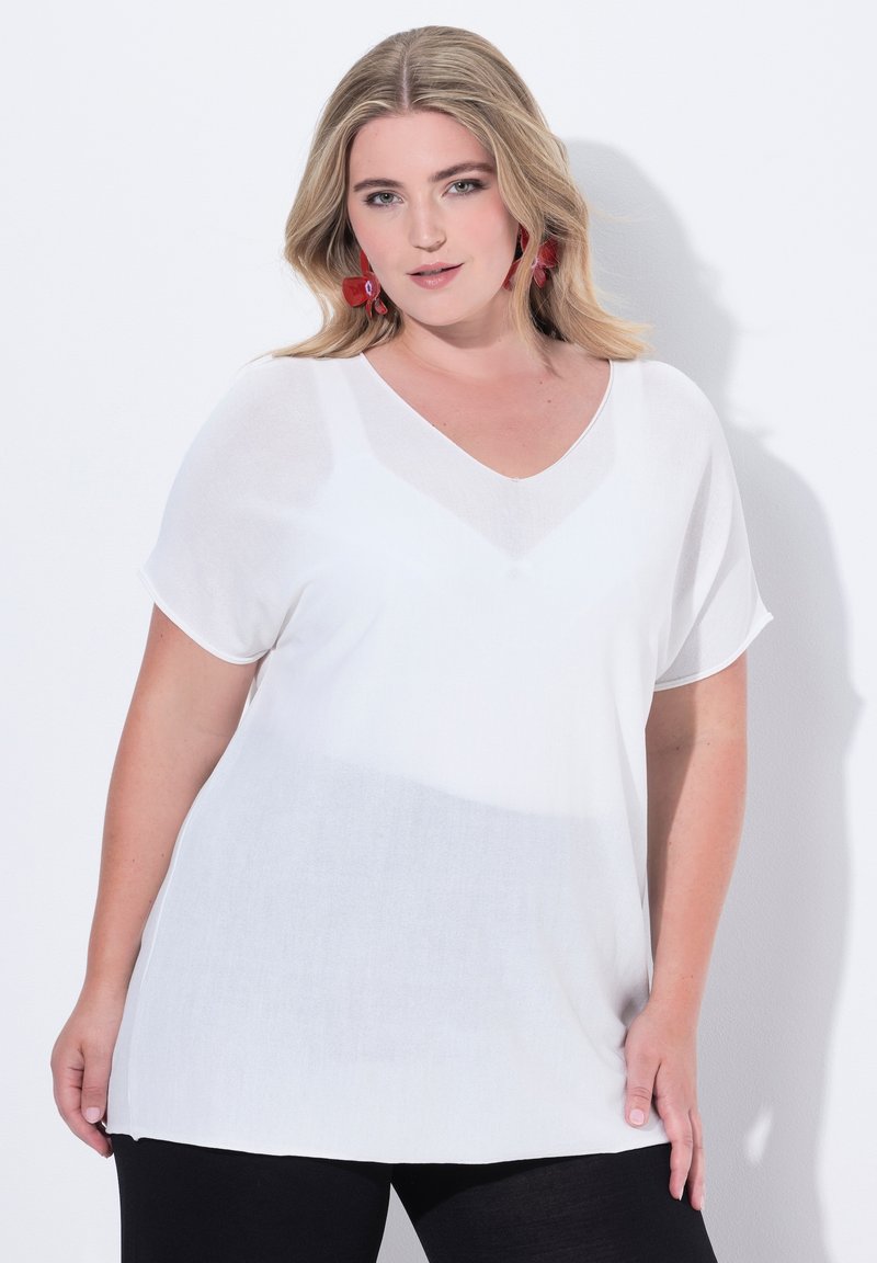 Blusa bianca leggera con scollo a V e maniche corte, caratterizzata da un sottile design gradient. Tessuto morbido, vestibilità comoda. Pantaloni neri.