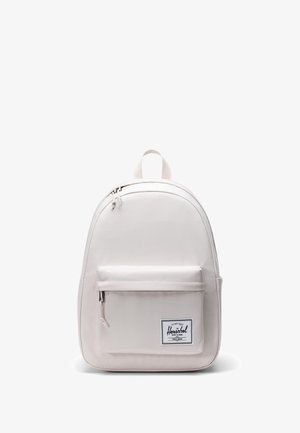 Sac à dos beige clair en tissu résistant, avec une forme arrondie, une poche zippée à l'avant et une poignée de transport en haut. Patch avec le logo Herschel visible.