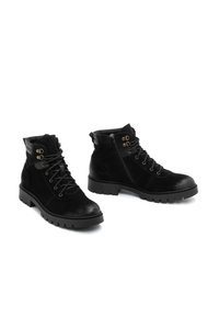 Botas de tobillo de ante negro con punta redonda, cordones en la parte delantera, cremallera lateral y suela de goma resistente. Presentan acentos de hardware en latón.