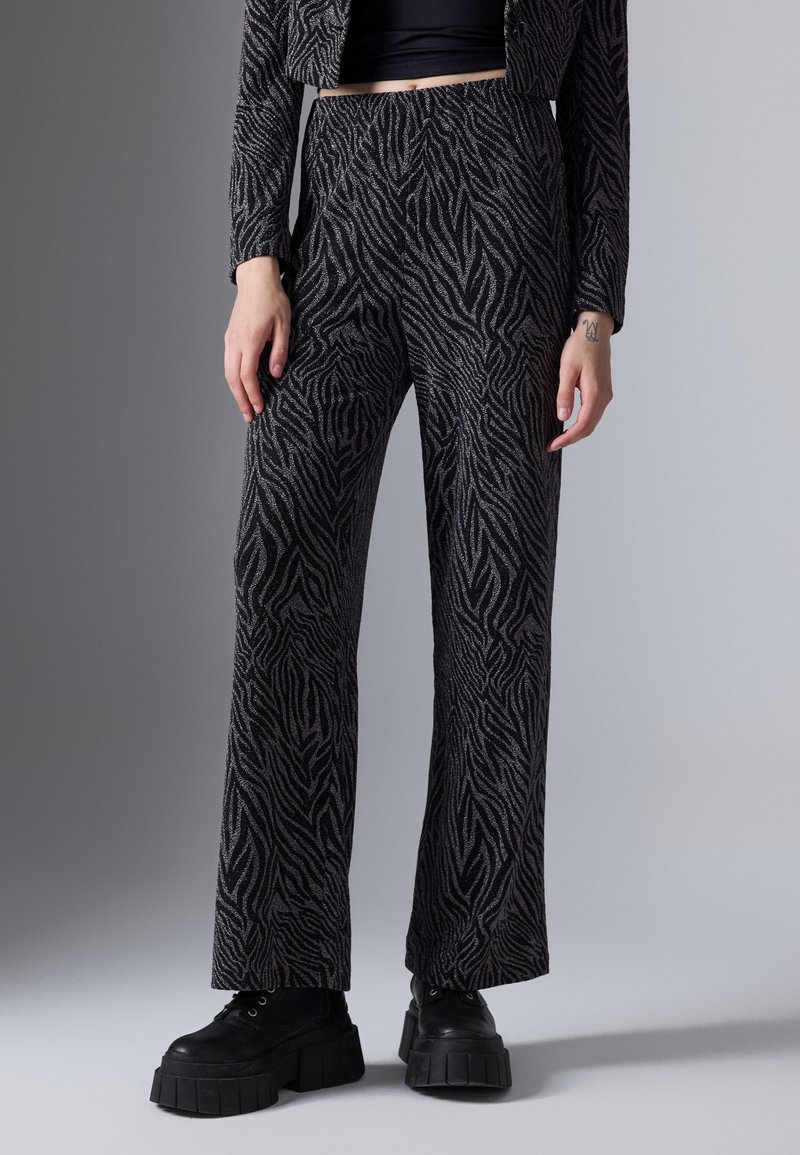 Gepatronde broeken in zwart en zilver zebra print, wijde pijpen, gestructureerde stof, gecombineerd met chunky zwarte platform schoenen.