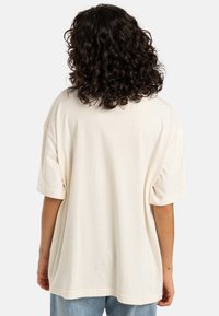 T-shirt ampio di colore crema realizzato in cotone morbido. Presenta maniche corte, scollo rotondo e una silhouette rilassata.