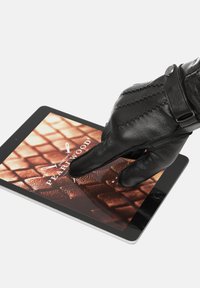 Crna kožna rukavica kuca po ekranu tableta koji prikazuje logo "Pearlwood" na teksturiranoj smeđoj pozadini. Tablet ima tanak dizajn.