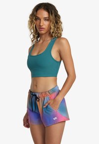 Top corto de canalé en verde azulado combinado con pantalones cortos de degradado multicolor que muestran tonos de naranja, rosa y azul; cuenta con una cintura elástica y cordón.