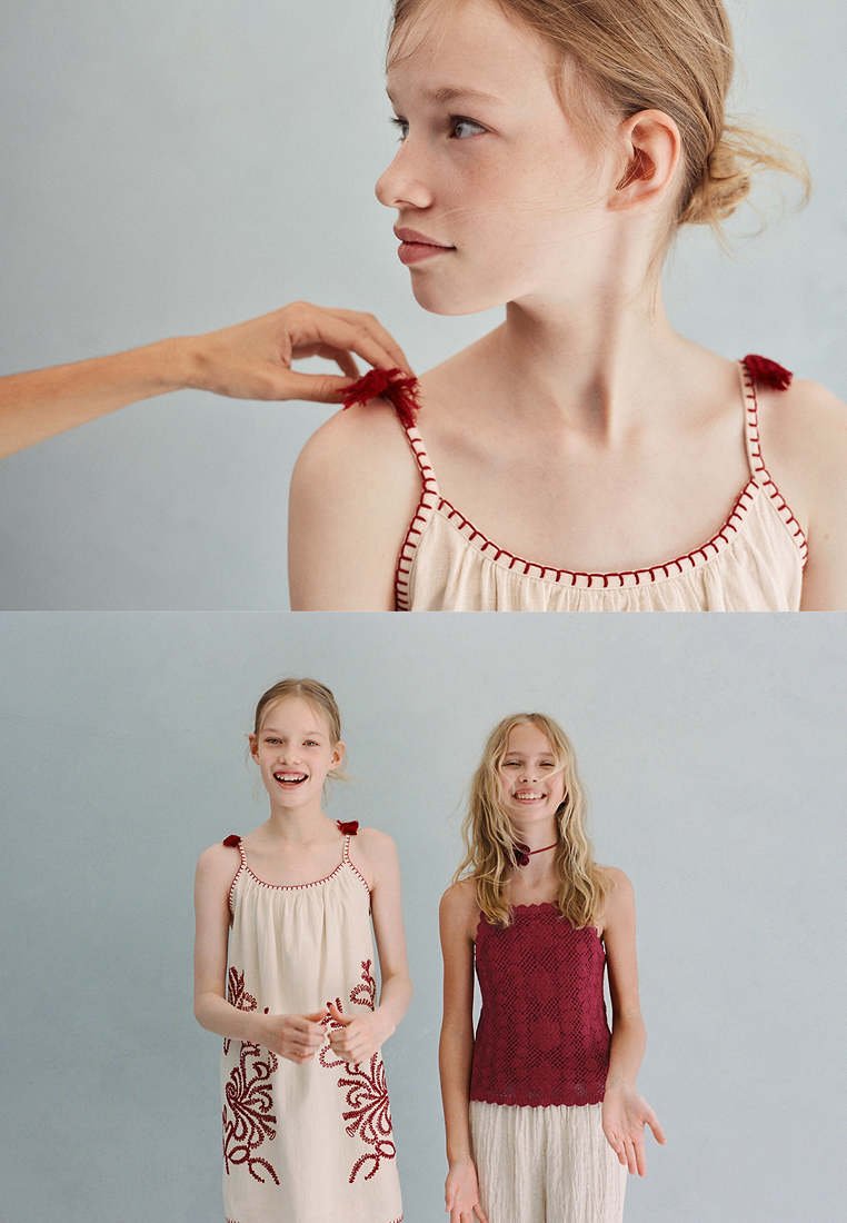 Jeune fille aux cheveux clairs portant une robe crème avec une broderie rouge, coiffée à la main ; deux filles souriantes se tiennent côte à côte en tenues décontractées.