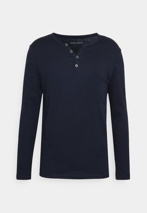 Marineblaues Henley-Shirt mit langen Ärmeln aus Baumwolle, mit rundem Halsausschnitt, einer Knopfleiste mit drei Knöpfen und einem glatten, strukturierten Finish.
