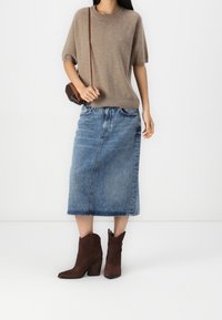 Bruine trui met korte mouwen, blauwe denim midi-rok en donkerbruine cowboylaarzen. Elegante, zachte texturen en een klassiek denimontwerp.
