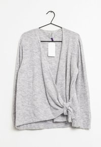 Šedý pletený svetr s překládaným předním dílem, s uzlem uvázaným v pase, dlouhými rukávy a měkkou texturou. Visačka visící u krku.