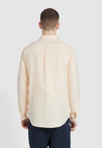 Lichtgestreepte gele blouse met lange mouwen van katoen, met een gebogen zoom en een rugplooi detail. Geknoopte manchetten en kraag.
