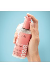 Bouteille transparente avec un distributeur à pompe rose, contenant un produit blanc et mousseux. Présente un texte en gras et un logo de marque professionnel.