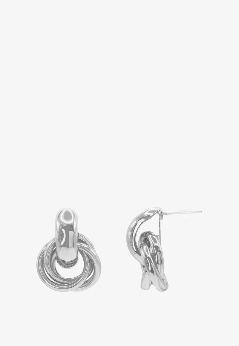 Boucles d’oreilles en métal ton argent avec design de boucles entrelacées et fermeture par tige, vues de face et de côté sur fond blanc.