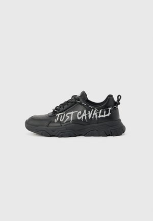 Melns biezpapēža sneakeris ar biezu zolīti un šņorēm, sānos ar baltu “JUST CAVALLI” tekstu graffiti stilā.