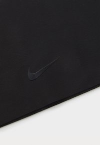 Crna tkanina, glatka tekstura, s mat crnim Nike swoosh logotipom, minimalistički dizajn, bez uzoraka ili dodatnih detalja.