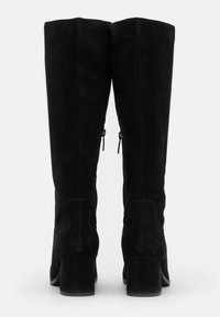 Botas altas de tacón negro de ante con un acabado liso, diseño hasta la rodilla y cierres de cremallera en la parte posterior. Los tacones cuadrados ofrecen estabilidad.