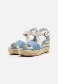 Sandales à talon en denim bleu avec une semelle en corde de jute, une sangle de cheville beige réglable et un intérieur lisse. Conception à bout ouvert.