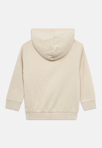 Beige hettegenser med hette, lange ermer, ribbestrikkede mansjetter og nederkant. Glatt tekstur med et enkelt design, med en sentrert søm på hetten.