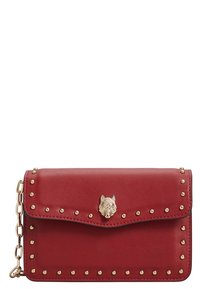 Červená kožená crossbody taška se zlatými hrotovými akcenty a dekoračním uzávěrem ve tvaru vlčí hlavy. Klopový design s řetízkem. Hladký povrch.