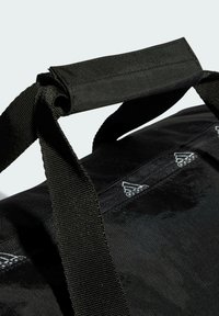 Bolsa de deporte negra con tejido resistente y correas gruesas y texturizadas. Presenta un logo y un patrón sutil a lo largo de la correa, con un acabado ligeramente brillante.