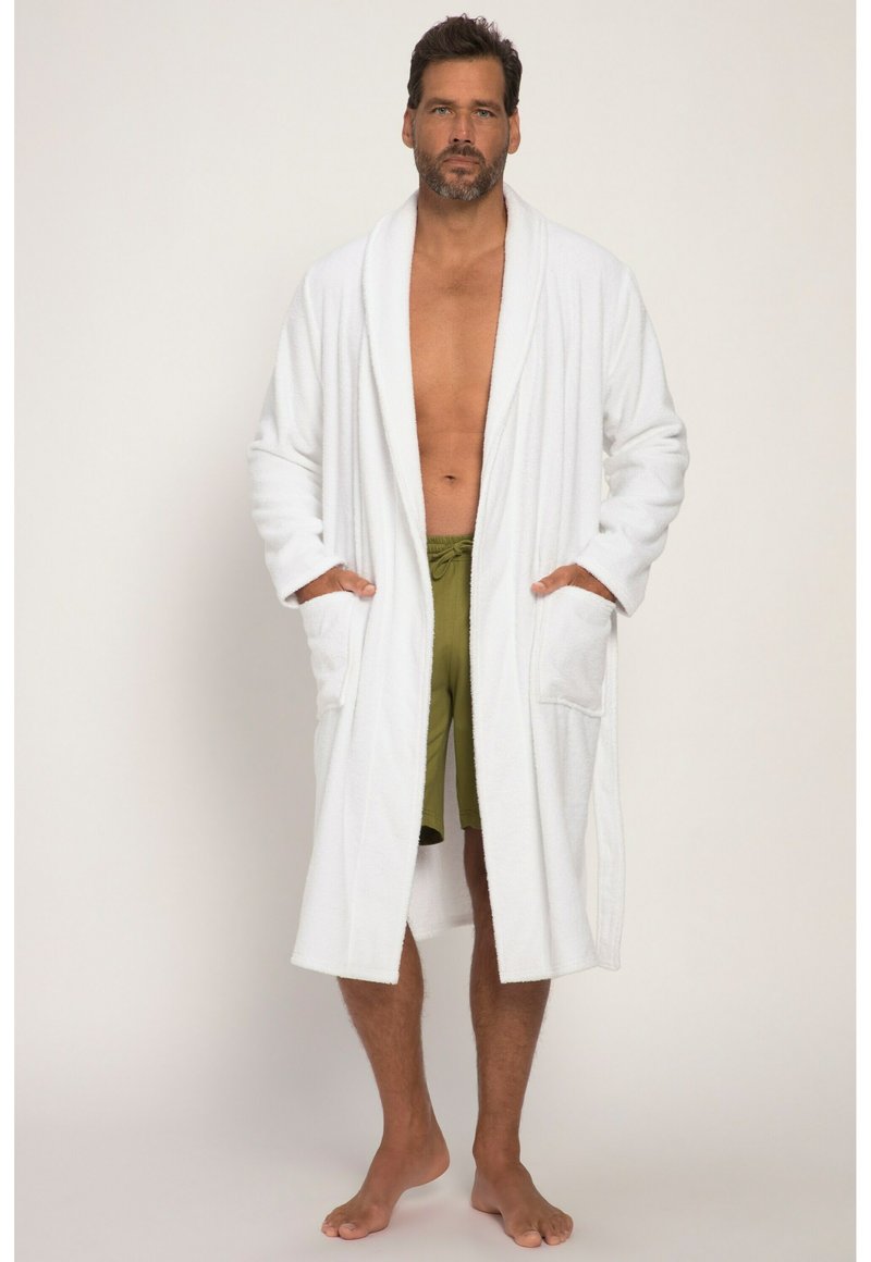 Accappatoio bianco in spugna con maniche lunghe, due tasche frontali e collo a scialle, indossato sopra pantaloni corta verde oliva.