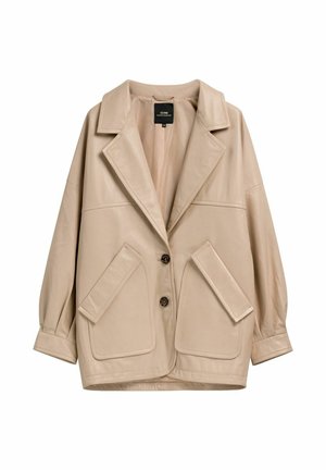 Beżowa, oversize kurtka z szerokimi klapami, dwoma zapięciami na guziki z przodu oraz dużymi, skośnymi klapami na kieszeniach po obu stronach.