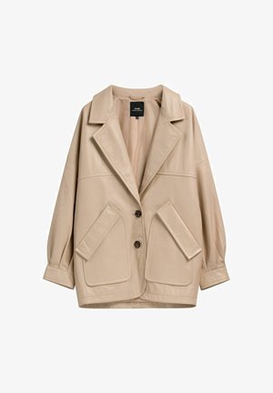Beżowa, oversize kurtka z szerokimi klapami, dwoma zapięciami na guziki z przodu oraz dużymi, skośnymi klapami na kieszeniach po obu stronach.
