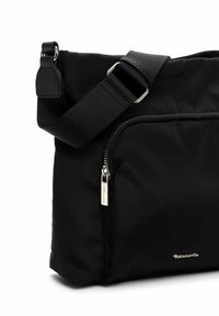 Melnā neilona plecu soma ar rāvējslēdzēja kabatu, regulējamu siksnu un sudraba krāsas apdari. Gluda tekstūra ar minimālu zīmola detaļu.