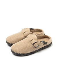 Zuecos de fieltro beige con punta redondeada, correa ajustable y suela de goma gris oscura que presenta costuras visibles a lo largo del borde.