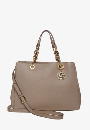 Beżowo-brązowa skórzana torebka z podwójnymi górnymi uchwytami ozdobionymi złotymi i żółwimi ogniwami łańcucha, odpinanym paskiem na ramię oraz okrągłą złotą zawieszką z logo MK.